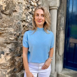 Nicola Sexton baby blue short sleeve knit with high neck and cuffed sleeves styled with white trousers